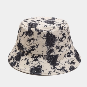 Close-up of off-white canvas bucket hat showing black ink splatter texture and reinforced seams