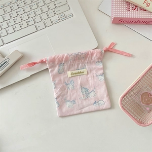 Macro shot of a light pink cotton drawstring pouch featuring cute blue cat prints and tag
