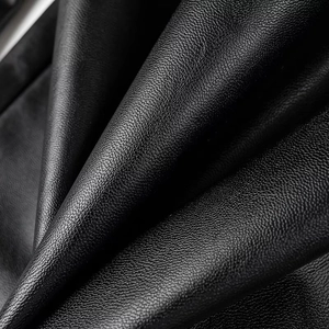 Macro shot of high-quality black faux leather texture with soft grain and subtle shine