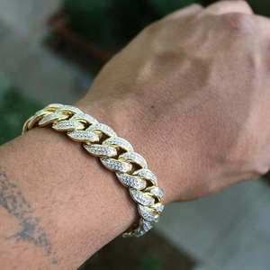 Gold Cuban link bracelet with sparkling rhinestones worn by a model in outdoor setting