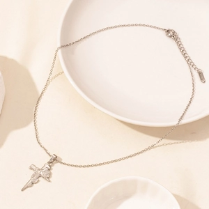 Detail of silver stainless steel necklace with rose wrapped cross pendant on ceramic dish