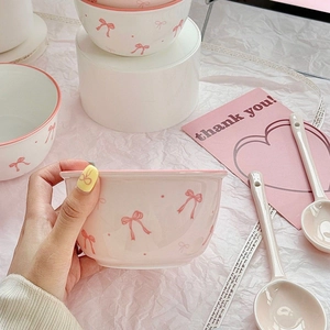 Cute pink ceramic bowl with bow pattern and matching spoon set on white stand