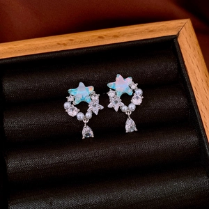 Macro view of star earrings featuring blue opal stones, pearls, and water drop pendants