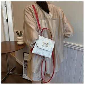 Detail of contrast color butterfly bag with metallic bow showing crossbody style