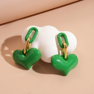 Detailed view of glossy green heart earrings on a white cloud-shaped ceramic display