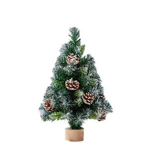 Miniature Christmas tree with snow-dusted green needles, pine cones and round wooden base