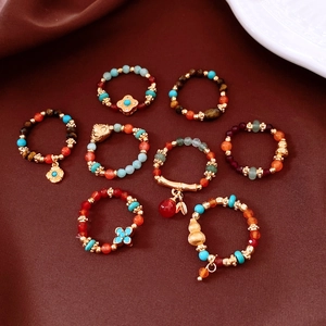 Detailed flat lay of vintage beaded rings with tiger eye and agate on dark red fabric