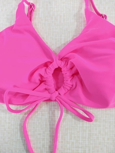Detail of rose pink halter bikini top with ruched cutout and bottom bow tie closure