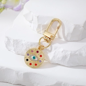 Detail of bohemian gold metal evil eye keychain with colorful rhinestones on stone background
