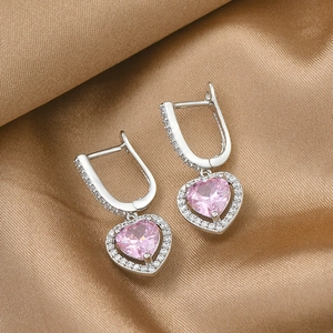 Macro detail of heart-shaped pink zircon earrings with white pave stones on golden silk