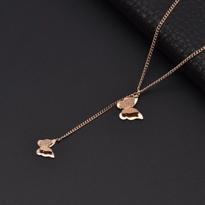 Rose gold Y-shaped necklace with double butterfly pendants and tassel on textured background