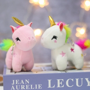 Close-up of plush unicorn charms with gold horns and rainbow hair on a gift box