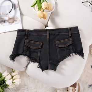Dettaglio degli shorts in denim nero con cuciture arancioni a contrasto e orlo sfrangiato