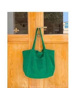 Detail of green corduroy tote bag featuring vertical texture and front pocket design