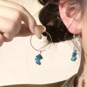 Detail view of silver hoop earrings featuring blue mineral stone beads on ear