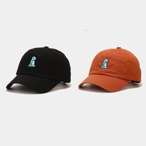 Detail of embroidered cartoon dinosaur pattern on black and orange cotton baseball caps