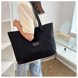 Detail shot of a black canvas tote bag showing the side view and the large capacity fit