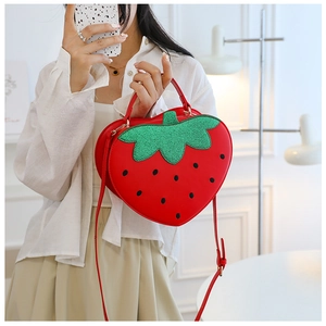 Detail of cute strawberry crossbody bag with green sequin leaves and polka dots
