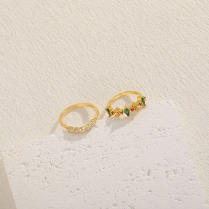 Close-up of 14K gold plated geometric rings with colorful zircons on a white stone