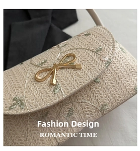 Détail de broderie de feuilles et fermoir papillon doré sur le sac en paille tressé