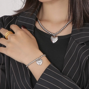 Detail of silver beaded heart pendant necklace and bracelet set worn by a model