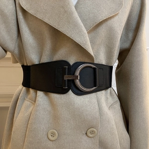 Vintage black elastic waist belt with silver engraved buckle on a beige wool coat