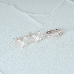Detail of S925 sterling silver butterfly earrings and paved zircon hoop set on white stone