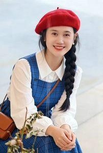 Close-up of a vibrant red wool beret styled with a blue plaid dress and brown bag