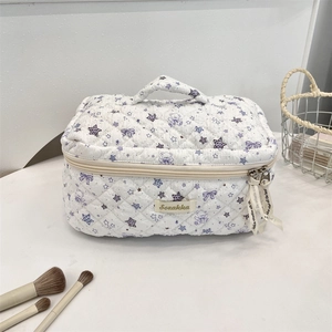 Detail of white quilted makeup bag with purple bear pattern and dual zippers