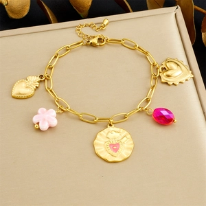 Detail view of gold charm bracelet with pink floral and red droplet heart pendants