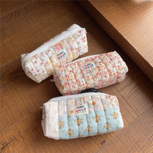 Three quilted floral pencil cases in yellow, pink, and blue with tulip labels on wood