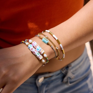 Detail of bohemian layered bracelets with colorful LOVE beads and gold-tone accents