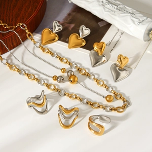 Flat lay of elegant gold and silver heart-shaped jewelry set with necklace and rings