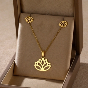 Detailed macro view of golden stainless steel lotus necklace and earring set in jewelry box