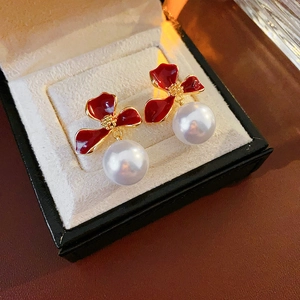 Detail of red flower pearl earrings with enamel finish on a jewelry box display