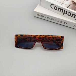 Detail view of tortoiseshell rectangular sunglasses on books with a 45-degree angle