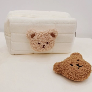 Close-up of soft white quilted plush stationery bag with a cute brown bear ornament