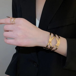 Detail view of hollow geometric gold bracelet and ring set on professional model