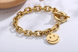 Detail of golden stainless steel chain bracelet featuring a smiley face and OT toggle clasp