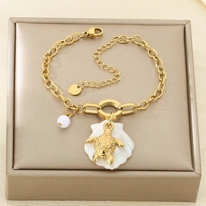 Detail view of gold ocean charms with sea turtle and shell on stainless steel chain