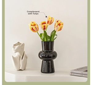 Detail of a sleek black geometric glass vase styled with vibrant tulips and art decor