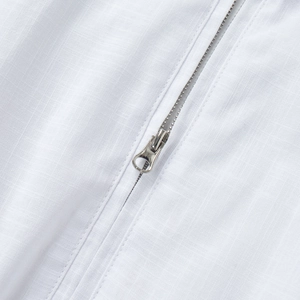 Macro shot of silver metal zipper and textured white fabric on a vest dress set