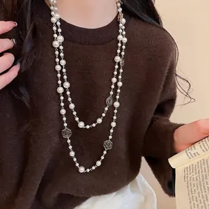 Elegant vintage double-layer pearl necklace with floral pendants on dark sweater