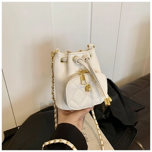 Detail of white quilted bucket bag featuring a gold camellia zipper pull and chain strap