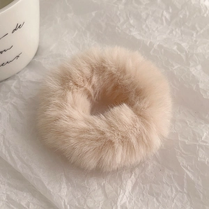 Close-up of soft plush beige scrunchie with faux fur texture on wrinkled paper