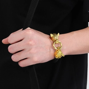 Detail of a braided leather bracelet with golden lion heads and a central metal ring