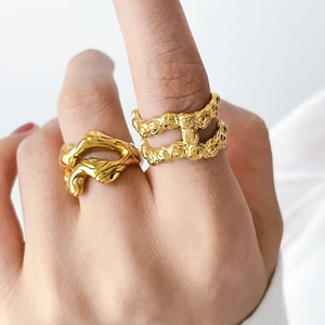 Detail of 18K gold-plated stainless steel lava rings with abstract fluid texture on model