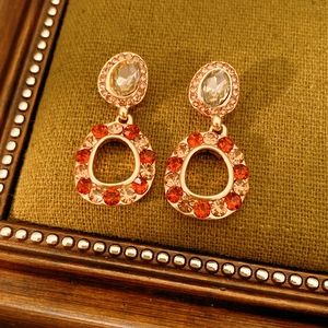 Detail view of vintage rose gold earrings with orange crystals on green fabric