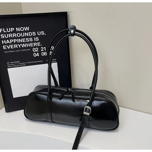 Detail of a black PU leather cylinder handbag with slim straps and silver hardware