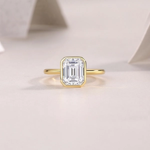 Detail of emerald cut moissanite in bezel setting on a gold plated silver band
